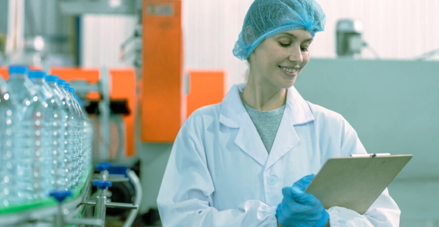 Caucasian female scientist working in laboratory at factory warehouse. Attractive woman chemist analysis of a chemical sample in the scientific research laboratory processing bottles of mineral water.