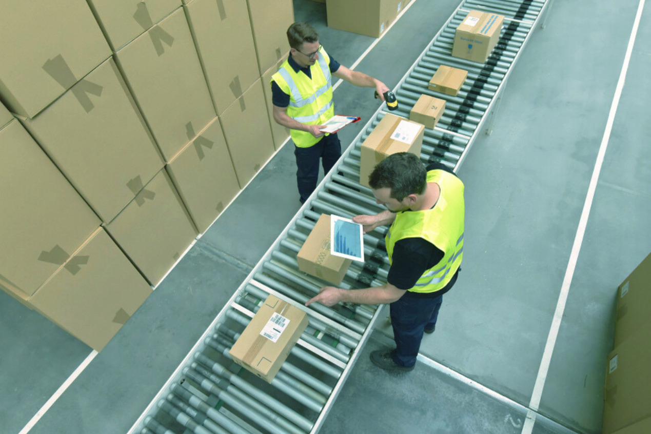 warehouse workers scanning packed packages along a conveyor belt direct to consumer fulfillment