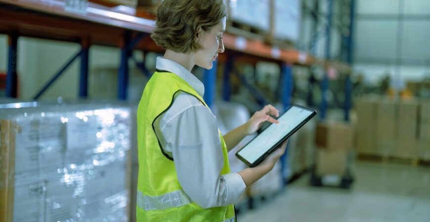 Worker in warehouse hold tablet check list perform inventory stock check goods boxes on the storage steel racking for annual report